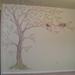 A soft Apple tree blooms with two robins carrying a ribbon with the baby's name on it over the crib. Mural by Ellen Leigh
