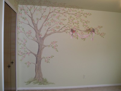 A soft Apple tree blooms with two robins carrying a ribbon with the baby's name on it over the crib. Mural by Ellen Leigh