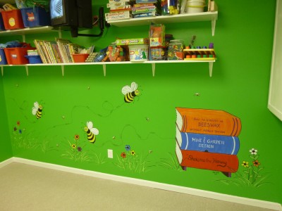 Spelling Bees. Cartoonish bees and a hive made out of books in the library at the day care. Mural by Ellen Leigh